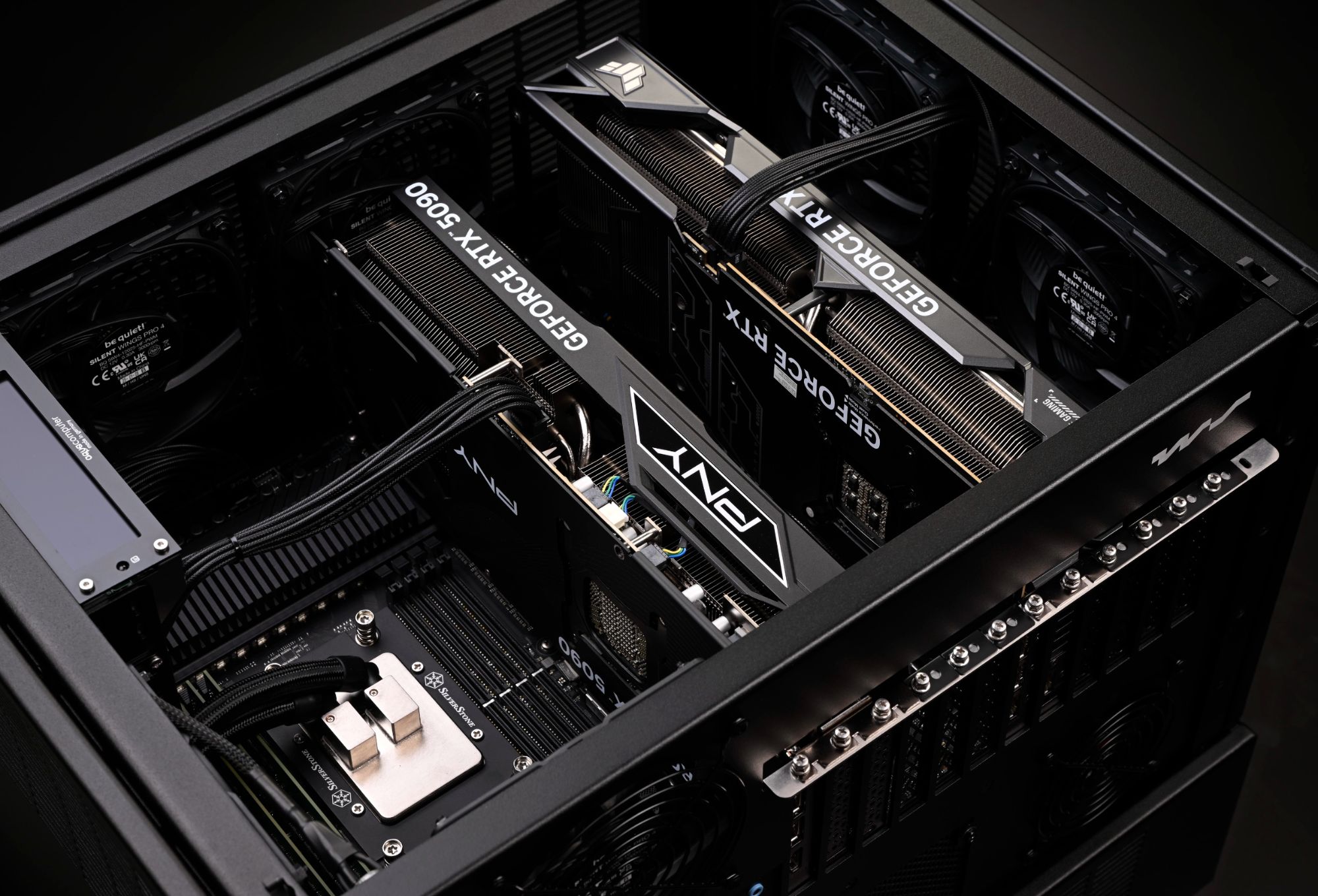 Indvendigt i en WS.COMPUTER-arbejdsstation: to GeForce RTX 5090-grafikkort, strømkabler med sleeving og en SilverStone CPU-køler i et sort kabinet